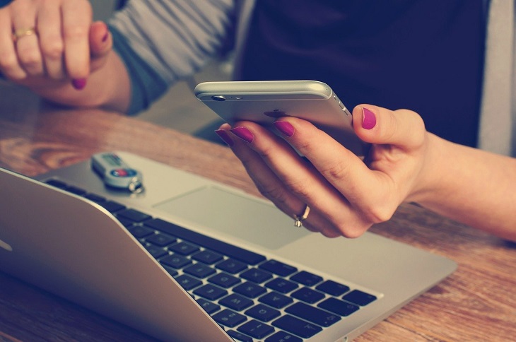 person using smartphone and laptop